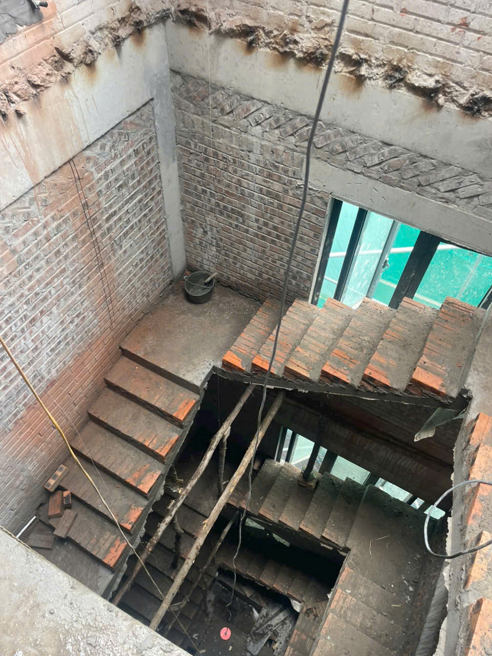 Cầu thang bê tông cốt thép đang xây dựng trong nhà thô tường gạch chưa hoàn thiện